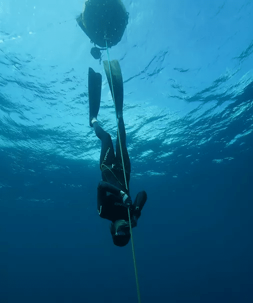 a person doing free dive with a rope